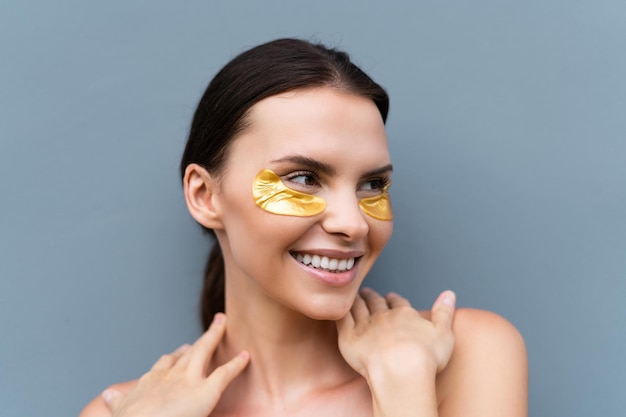 Close beauty portrait of a topless woman with perfect skin and natural makeup shiny patches under the eyes to moisturize the skin and relieve puffiness of the face