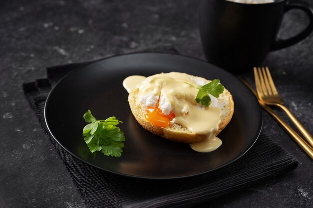 Close of a black plate with poached egg on dark background