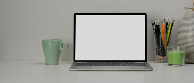 Close cup view of simple workspace with blank screen laptop, stationery, mug, decorations and copy space