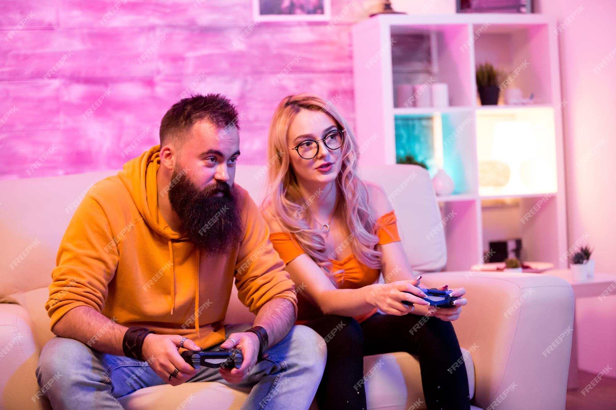 Premium Photo  Boyfriend cheering her beautiul girlfriend while she's playing  online games using wireless controller. room with neon light.