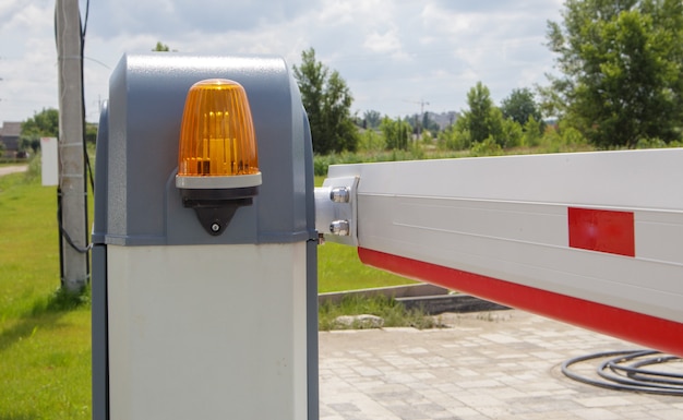 Close the gate. Automatic security system. Automatic entry system. Yellow light signal with a street barrier. Barrier gates Automatic security system.