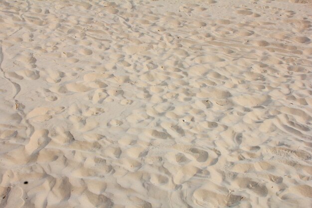 Photo close image of sand with several marked footprints ideal for promoting beach vacations