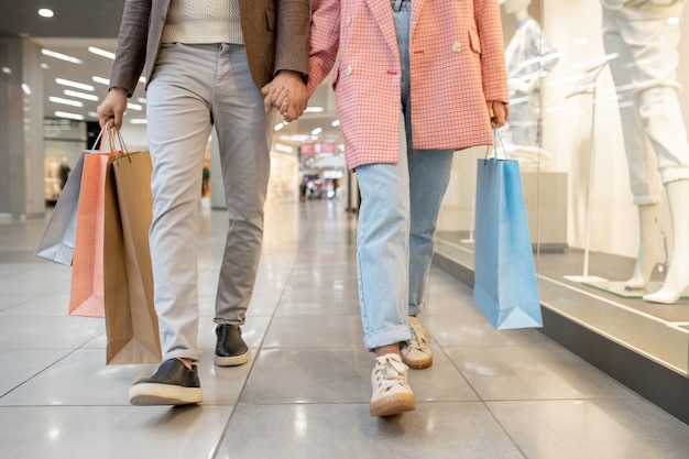 Close-p van jong koppel hand in hand en samen wandelen in winkelcentrum met aankopen