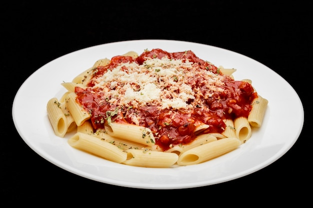 Close in penne meal with red sauce and grated cheese, black background