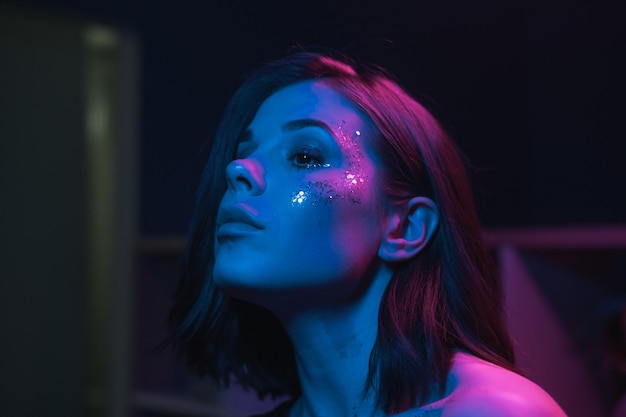 Close photo of a beautiful woman with bright makeup at a night party with purple