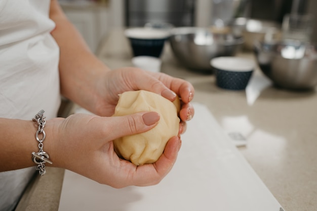 Una foto ravvicinata delle mani di una donna che tiene in mano pasta frolla in cucina