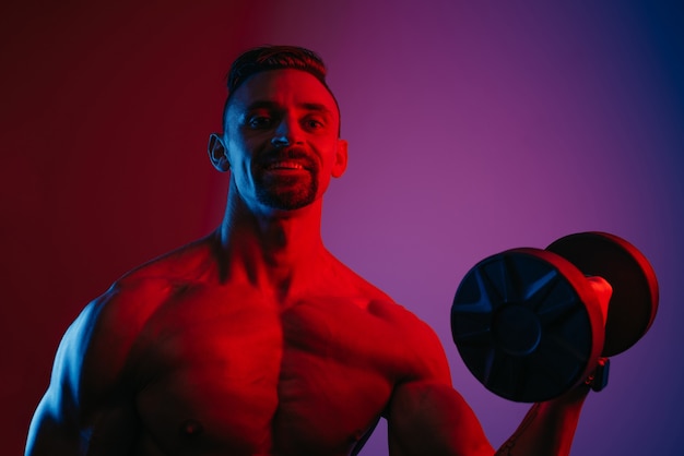 A close photo of a muscular man with a beard who is doing bicep curls with dumbbells under blue and red lights