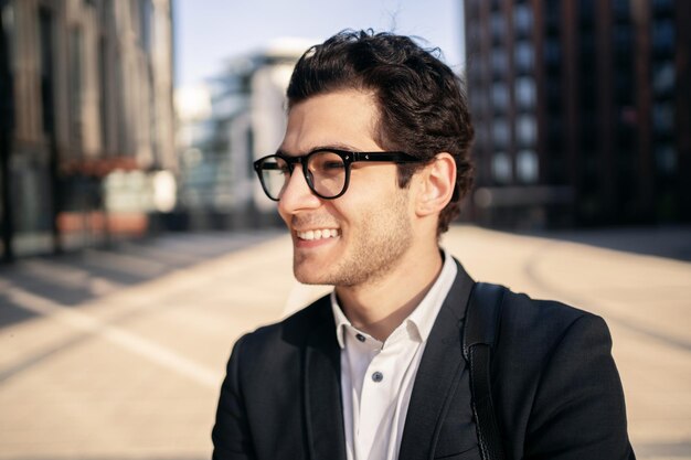 A close portrait of a businessman man in glasses and a formal suit smiling looking away