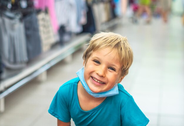 Close portrait cute smiling blue eyed freckled blond boy artistic facial expressions gestures wearing sanitary face mask shopping supermarket New normal safety health protection covid 19 quarantine