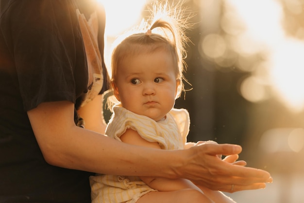 A close portrait of a female toddler at the hands of a mommy