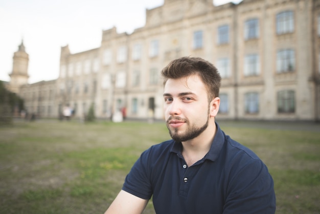 Close portrait of a man with a beard on the back of the university building.