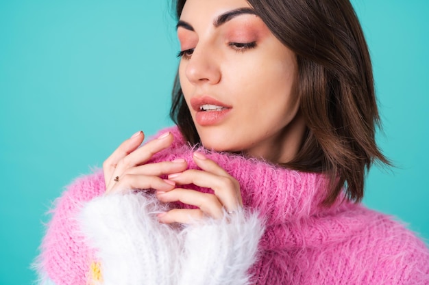 Close portrait of a young woman in a sweater on blue with graceful hands, long thin fingers