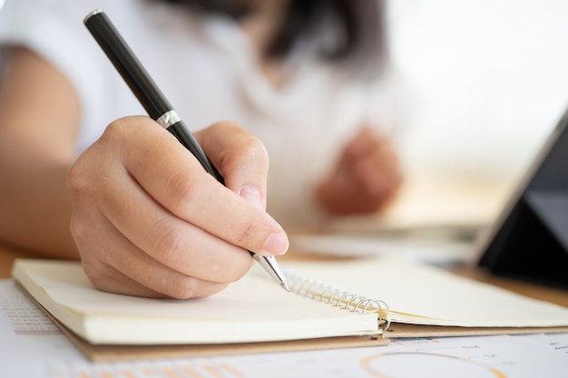 Close shot of businesswoman hands holding a pen writing something