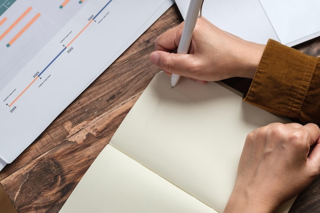 Close uop woman hand writing on notebook at worknig desk at home