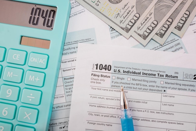 Крупный план 1040 налоговых форм с калькулятором, долларами и ручкой.