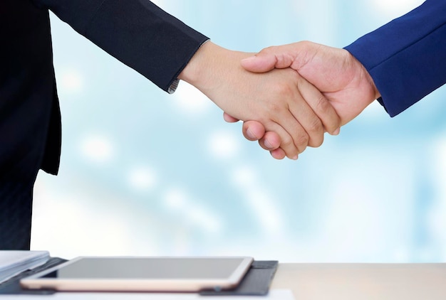 Close up 2 business people shaking hands during meeting in office room