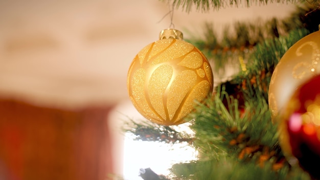 Close-up 4k-beelden van gouden sprankelende kerstbal die aan de kerstboom in de woonkamer hangt en ronddraait