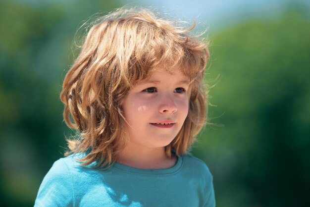 Close-up aantrekkelijke kinderen gezicht kind emoties concept portret van jonge lachende jongen buiten vervagen backg