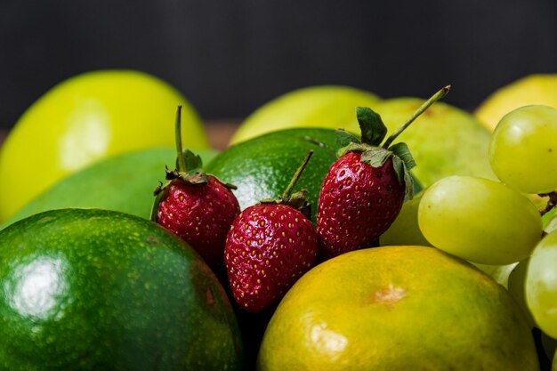 Close-up Aardbei onder groene vruchten op een houten achtergrond gezond voedsel concept