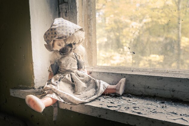 Close-up of abandoned doll by window