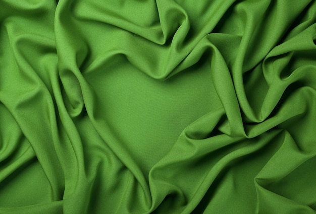 ハート型の緑の折り畳まれた生地のプリーツの抽象的なテキスタイルの背景をクローズアップ、真上に高い上面図