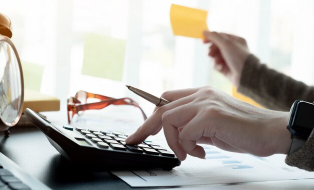 Close up accountant working on desk using calculator for calculate finance report in office