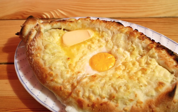 Close-up Adjaruli Khachapuri, een beroemde Georgische kaas en eierbrood geserveerd op houten tafel