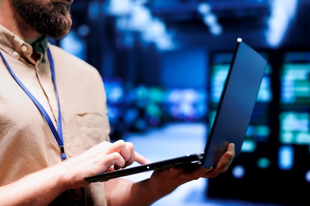 Close up of admin using laptop to check electronics in blockchain technology application specific integrated circuit server rig clusters. Focused employee checking for issues in crypto mining farm