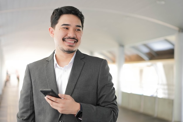 close up adult middle eastern businessman hold smartphone and standing outside office in relax time for lifestyle business concept