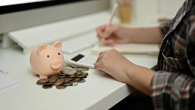 Close-up afbeelding Piggy bank en munten op tafel met vrouwelijke maandelijkse onkostenrekeningen maken