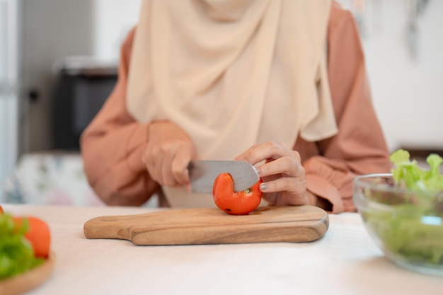 Close-up afbeelding van een moslimvrouw die ingrediënten bereidt voor haar salademengsel in een keuken