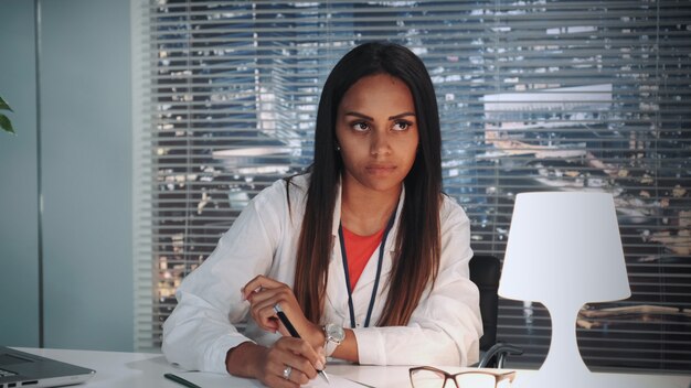 Close-up of african American psychologist attentively listening to patient's story and writing notes