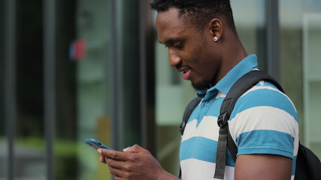 Close up african american young attractive man using phone on street shot of man using smartphone in city