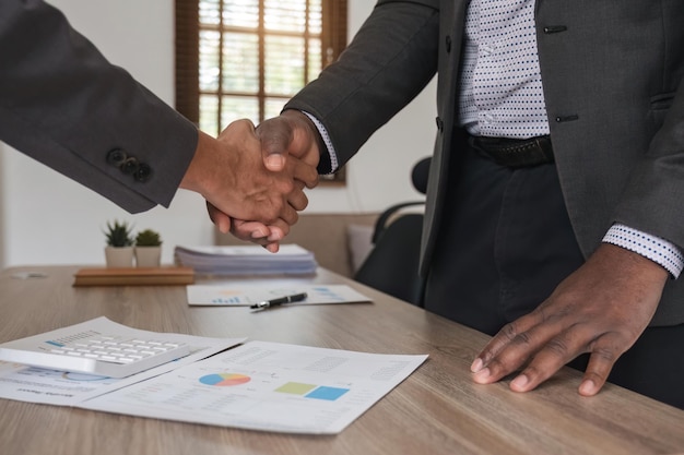 Close up of african business man and asian man shaking hands while at the office