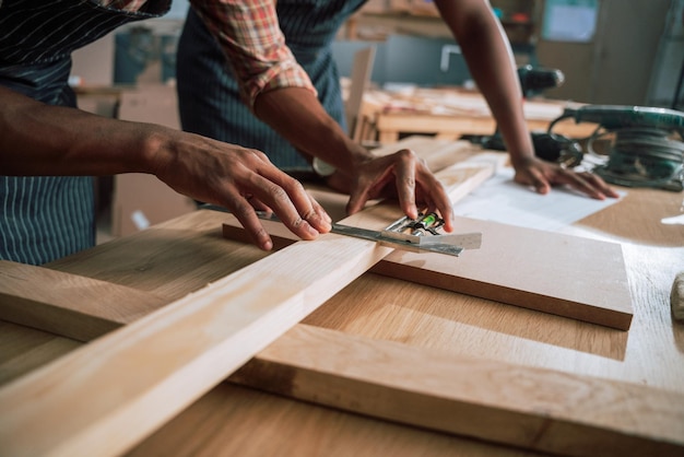 Photo close up of an african male lining up a piece of wood for carpentry project in woodwork factory