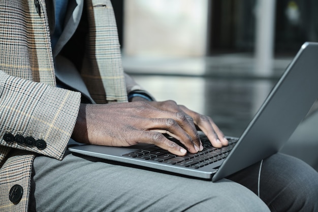 Close-up of African man typing on laptop and working online