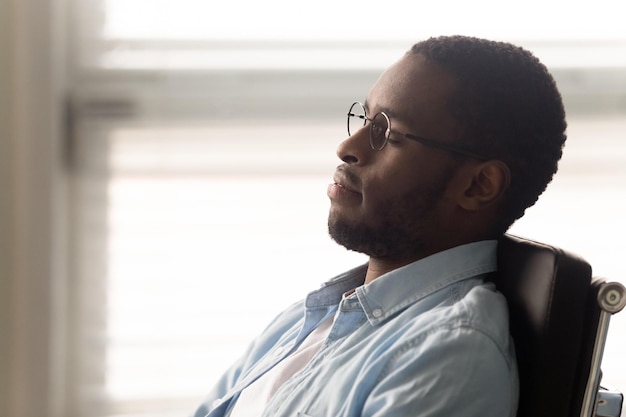 Close up african office worker closed eyes resting enjoy break\
dreaming about future career growth seated on ergonomic chair\
correct lumbar support of posture maximum comfort during sitting\
concept