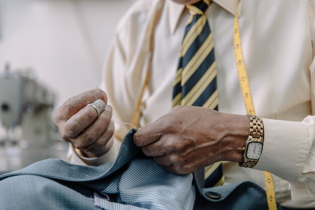 Close up of an aged Mexican tailor sewing by hand on local business