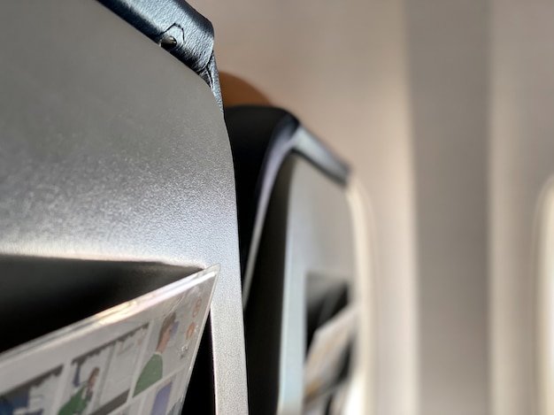 Primo piano dei sedili dell'aereo con le istruzioni di sicurezza a bordo che fuoriescono dalla tasca posteriore. concetto di viaggio e turismo.
