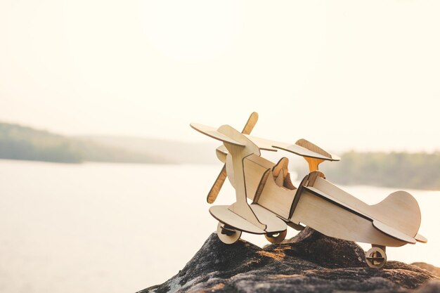 Photo close-up of airplane model on rock by lake against sky