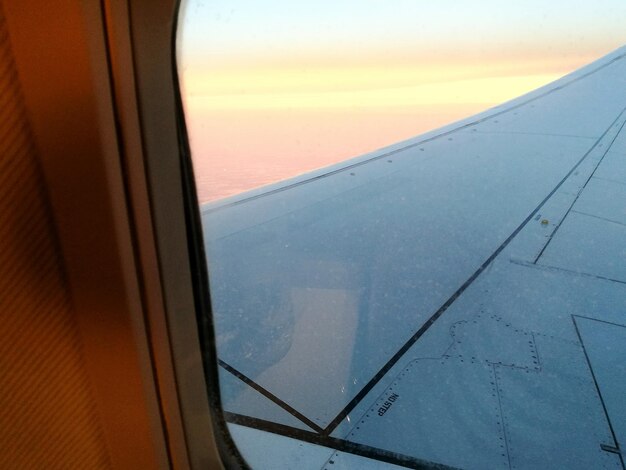 Close-up of airplane window against sky during sunset