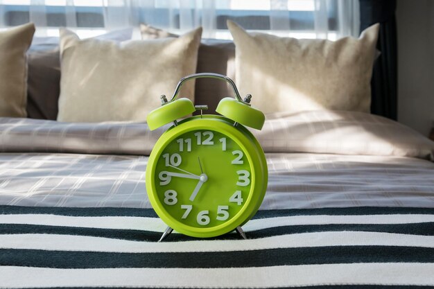 Photo close-up of alarm clock on bed at home