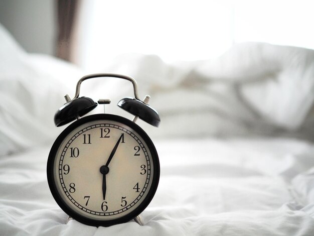 Close-up of alarm clock on bed at home