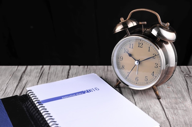 Photo close-up of alarm clock and diary on table