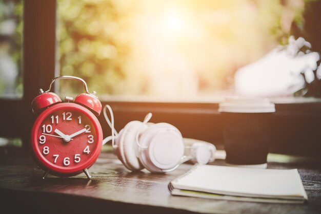 Photo close-up of alarm clock and headphones on table at home