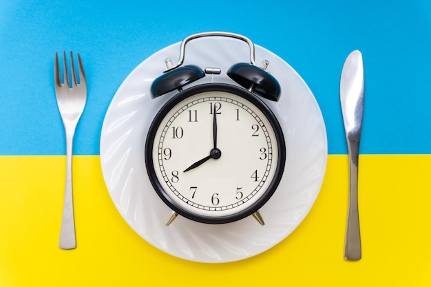 Photo close-up of alarm clock in plate on colored background