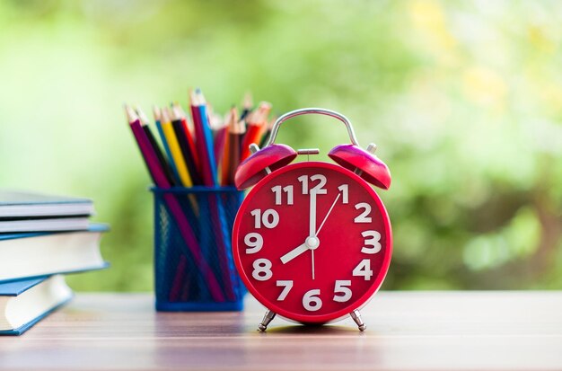 Photo close-up of alarm clock with colored pencils and books at home