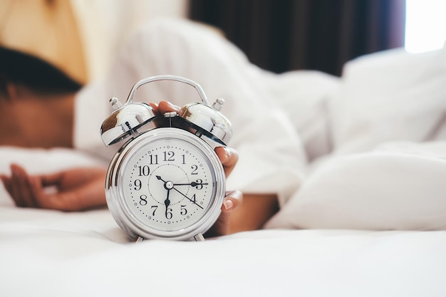 Foto close-up della sveglia e della donna a letto