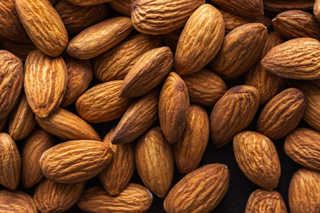 Close up almonds on dark wooden table. Organic health protein vegetarian food concept. Background