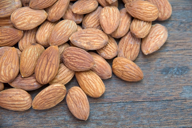 Close up of almonds grain roast on wood background with green leaves